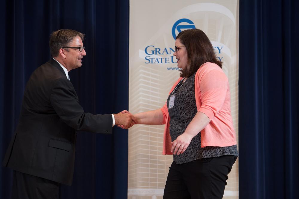Doctor Smart shaking hands with an award recipient in a coral sweater
